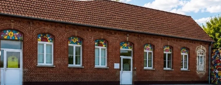 Le bâtiment en briques aux vitraux colorés et la cour de récréation